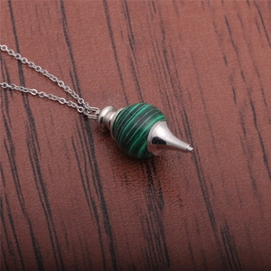 Macro shot of malachite stone pendant with silver filigree cap on a metal chain