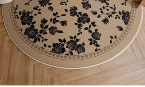 Detail of round beige rug with black rose pattern on light herringbone wood flooring