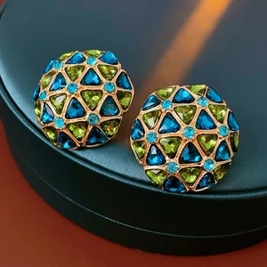 Detailed close-up of vintage gold earrings with blue and green crystals in a jewelry box