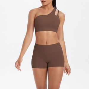 Detail of dark brown one-shoulder sports bra and high-waisted fitness shorts on model