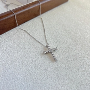 Detailed close-up of a silver S925 cross necklace with sparkling zircon on a jewelry box