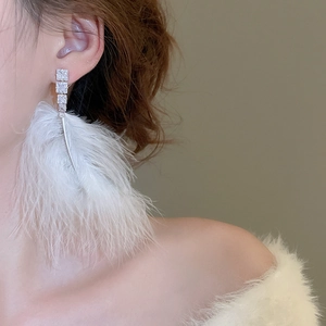 Macro view of white feather tassel earrings with sparkling cubic zirconia inlay detail