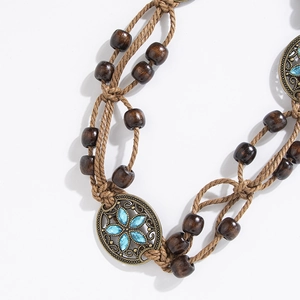 Detailed close-up of Bohemian woven belt showing dark wood beads and blue flower pendant