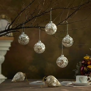 Silver multifaceted and ribbed glass Christmas baubles hanging on festive branches