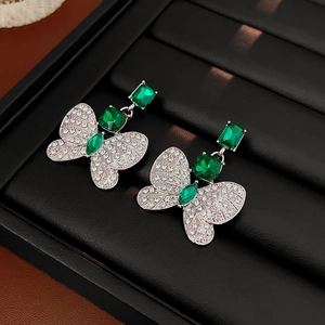 Vue détaillée de boucles d'oreilles gemmes vertes carrées avec ailes de papillon en cristal