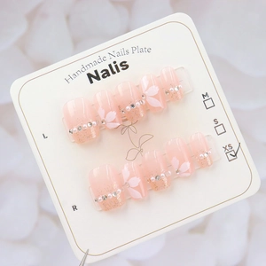 Detailed view of pink gradient press-on nails with camellia flowers and pearls