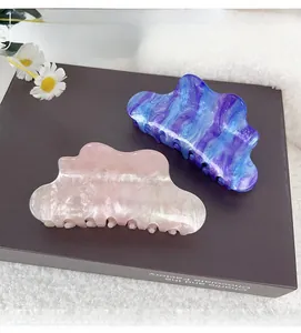 Detail view of cloud-shaped marble hair claws in blue and pink with glitter finish