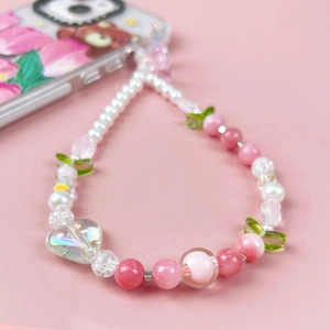 Close-up of pink tulip beaded phone strap with acrylic heart and leaf charms on pink background