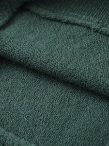 Macro detail of dark green knit fabric texture showing fine soft wool fibers