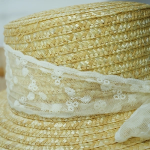 Close-up of fine straw texture and white lace embroidery on summer sun hat