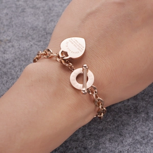 Vue macro d'un bracelet en acier inoxydable or rose avec pendentif cœur gravé d'un verset