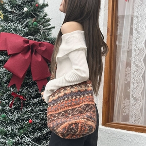 Close-up of a plush knit tote bag with ethnic jacquard patterns worn by a model