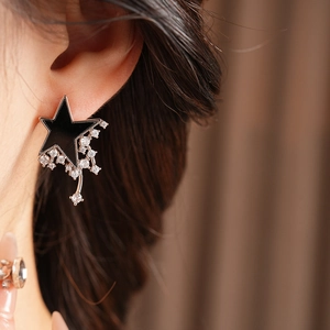 Close-up of model wearing black star earrings with silver edges and zircon tassels