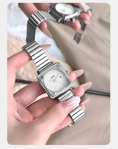 Dettaglio orologio quadrato argento con datario e cinturino elastico in acciaio inox