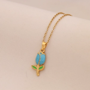 Vergoldete Titanstahlkette mit blauem Tulpen-Emaille-Anhänger auf beigem Stoffhintergrund