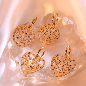 Gold tree of life earrings set with colorful crystals on a pink silk background