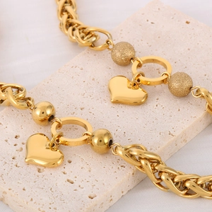 Golden heart pendant chain necklace on travertine stone with luxury polished beads