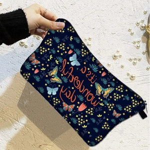 Detail of blue butterfly cosmetic bag with It's a wonderful day text held by hand