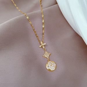 Detail of gold necklace featuring triple-stacked flower, star and clover pendants
