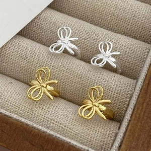 Macro shot of gold and silver bow-shaped stud earrings in a soft grey velvet jewelry box