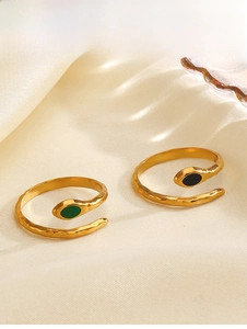 Dettaglio di anelli serpente vintage dorati con pietre ovali in smalto verde e nero