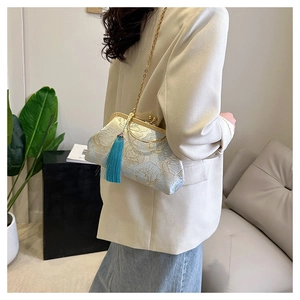 Detail of blue embroidered silk handbag featuring a floral pattern and long silk tassel