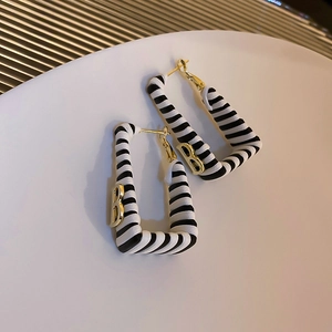Macro shot of striped square hoop earrings with gold metal B initial and silver pin