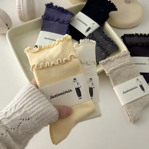 Set of ruffle cuff cotton crew socks in pastel colors displayed on a cozy cream tray