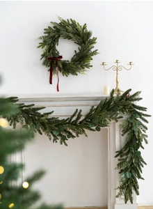 Christmas PE wreath and garland set with red velvet bows on a classic white fireplace