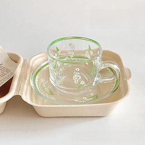 Detail view of transparent glass coffee cup set featuring green lily of the valley floral prints