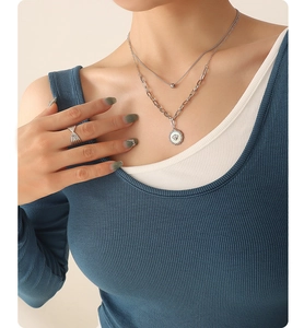 Detail einer silbernen Doppelkette mit Bienenanhänger und Perlenkette für Damen