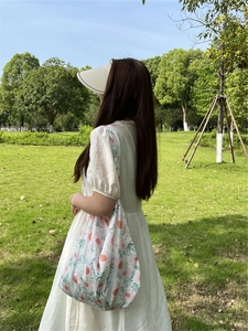 Floral print cotton tote bag in light green shown in an outdoor lifestyle setting