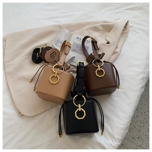 Flat lay of vintage drawstring bucket bags in black, brown, and beige with gold hardware