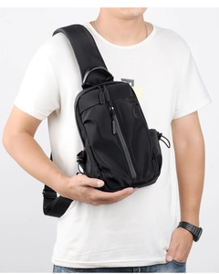 Front view of a black multi-functional chest bag with grey zippers on a male model