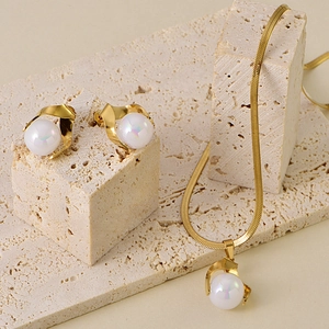 Elegant gold-tone jewelry set with iridescent pearls displayed on a natural stone base