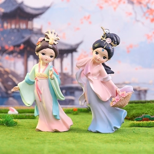 Pair of resin ancient Chinese girl figurines in pink and green attire on grass