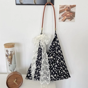 Detail view of floral canvas tote bag featuring lace bow and faux wood handle