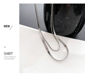 Detail of silver double-layered necklace featuring herringbone and bead chain layers