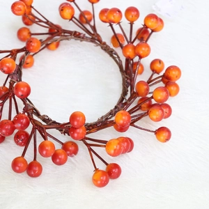 Close-up of artificial orange and red berry wreath for autumn candle ring decoration