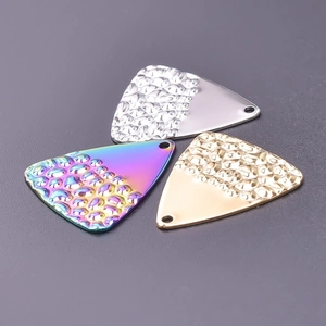 Macro view of triangular stainless steel charms with hammered textures in silver and gold