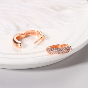 Rose gold micro-pave cubic zirconia hoop earrings displayed on a ceramic dish