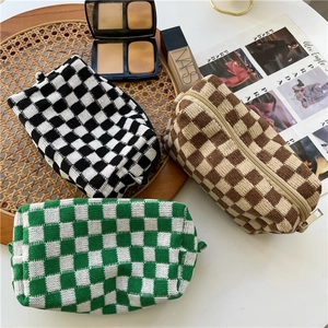 Three knitted checkerboard makeup bags in black, brown, and green with zipper closure
