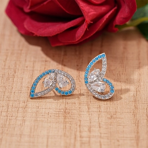 Detail of silver butterfly earrings with blue and white zircons on a wooden table
