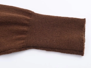 Macro detail of the dark brown knitted sweater cuff with fine vertical ribbed texture