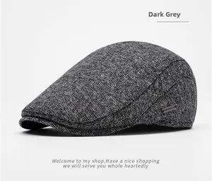 Detail of dark grey newsboy hat with textured woven fabric and small metal logo plate