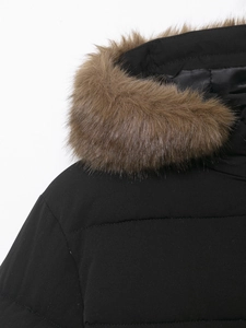 Gros plan détaillé du col en fausse fourrure brune sur un manteau d'hiver noir mat