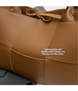 Macro shot of brown leather woven texture and detailed stitching on large tote bag