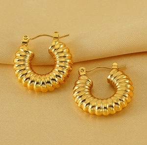 Detailed macro view of gold-plated croissant hoop earrings with spiral ribbed texture