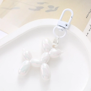 Detail of white iridescent balloon dog charm with metallic hook on a display tray