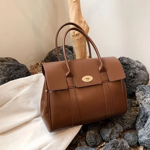 Detail of a brown leather tote bag with a classic metal twist lock and refined texture